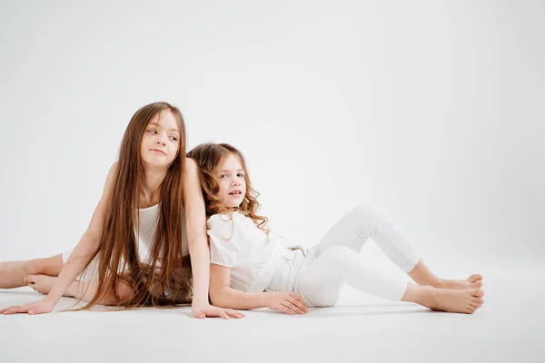 Δύο μικρά κορίτσια με μακριά μαλλιά με άσπρα ρούχα. αγάπη μεταξύ αδελφών. — Φωτογραφία Αρχείου