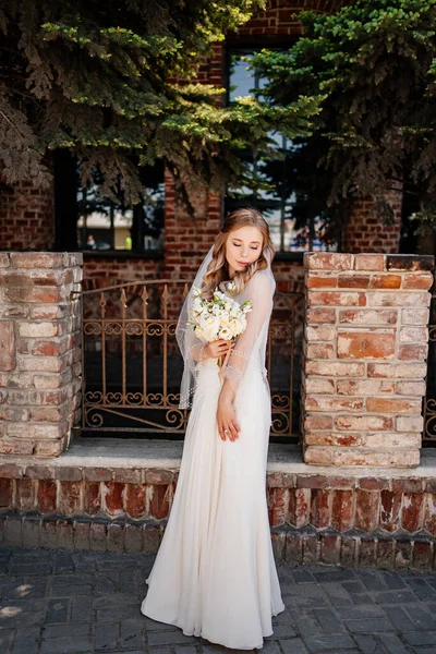 In voller Länge. glückliche und schöne Braut mit einem Blumenstrauß am Zaun. — Stockfoto