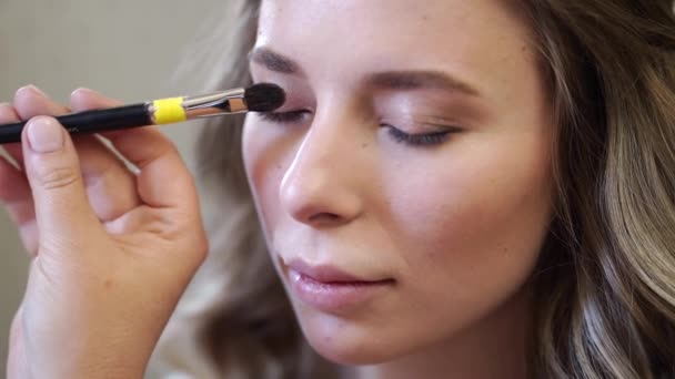 Ein schönes Mädchen mit langen Haaren machen Augen Make-up. — Stockvideo