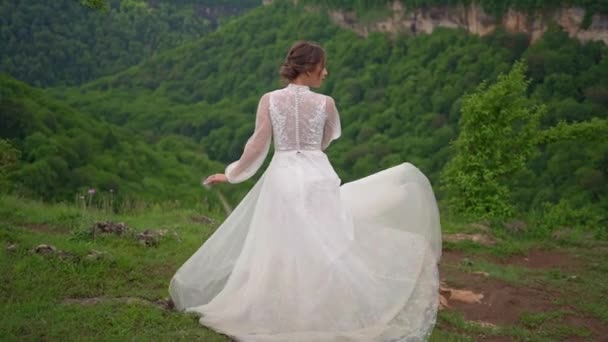 Φωτογράφιση γάμου στα βουνά. η νύφη γυρίζει στο λιβάδι. — Αρχείο Βίντεο