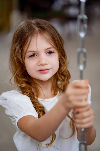 De près. jolie fille en vêtements blancs monte sur balançoire. rêves d'enfants. — Photo