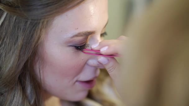 Een mooi meisje met lang haar doen oog make-up. — Stockvideo