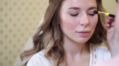 Uzun saçlı güzel bir kız fırçayla göz makyajı yapıyor.. 
