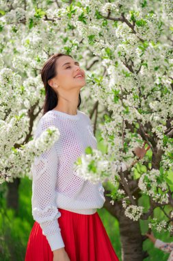 Çiçek açan ağacın yanında güzel genç bir kadın. Doğal kozmetik ürünleri ve parfümler. 