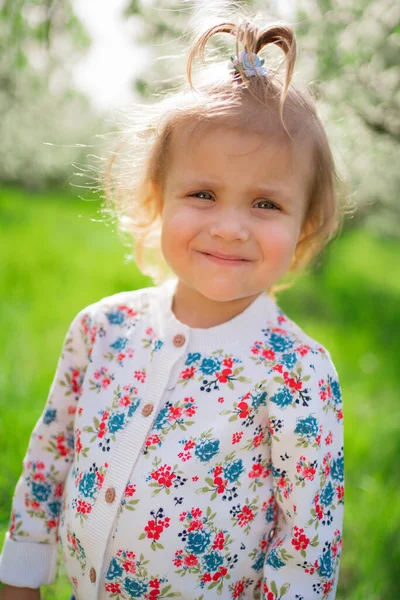 Malá roztomilá dívka na zeleném trávníku v parku. — Stock fotografie