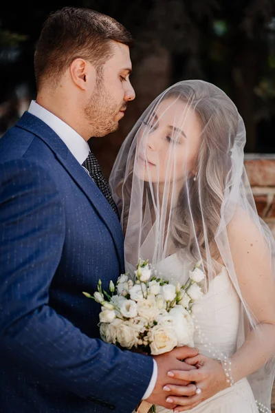 De lieve bruid onder de sluier en bruidegom. mooi en romantisch pasgetrouwden. — Stockfoto