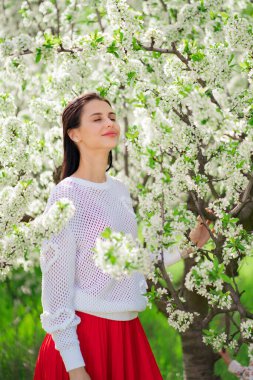 Çiçek açan ağacın yanında güzel genç bir kadın. Doğal kozmetik ürünleri ve parfümler. 