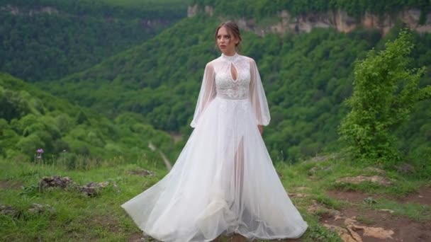 Eine schöne Frau in einem Hochzeitskleid und schwarzen Stiefeln posiert in den Bergen. — Stockvideo