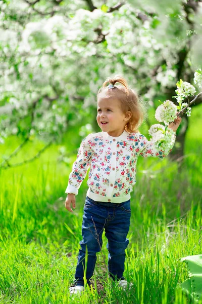 Niña se para en el árbol floreciente en el jardín. alergias estacionales en niños. —  Fotos de Stock