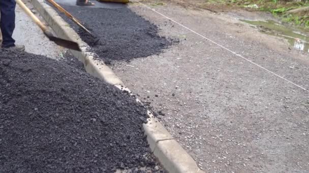 Los trabajadores con la pala ponen el asfalto en el camino. — Vídeos de Stock