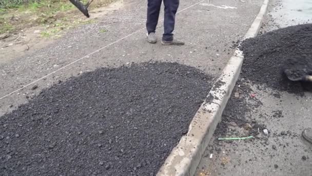 Arbetare med en spade lägger asfalt på en väg. — Stockvideo