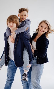 Mavi elbiseli iki oğlu olan bir anne fotoğraf çekimi için poz verir.