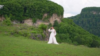 Düğün fotoğrafları dağlarda çekiliyor. Gelin dağlarda duruyor. Quadcopter ateş ediyor