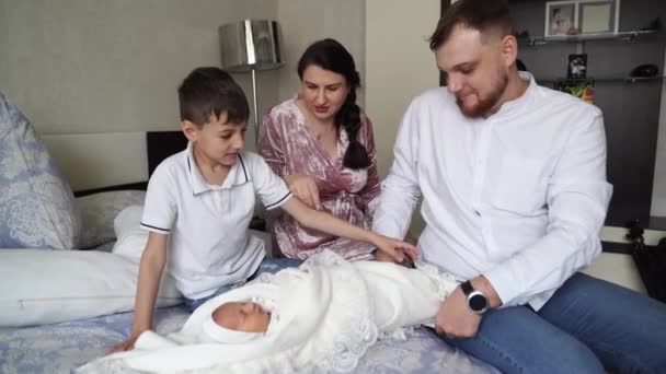 Den första dagen av den nyfödda hemma. Lycklig familj med ett litet barn i sovrummet — Stockvideo