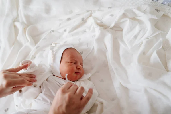 Мамы руки снимают одежду с новорожденного. — стоковое фото
