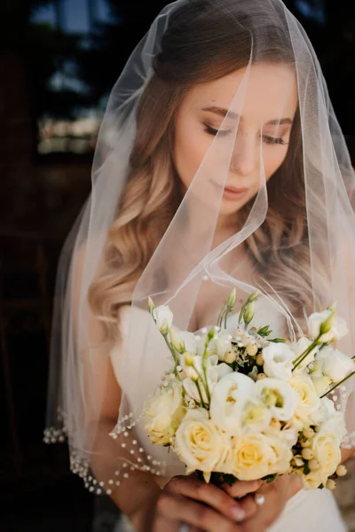 Vacker brud med långt vågigt hår under slöjan utanför. Bröllopssminkning. — Stockfoto