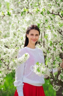 Çiçek açan ağacın yanında güzel genç bir kadın. Doğal kozmetik ürünleri ve parfümler. 