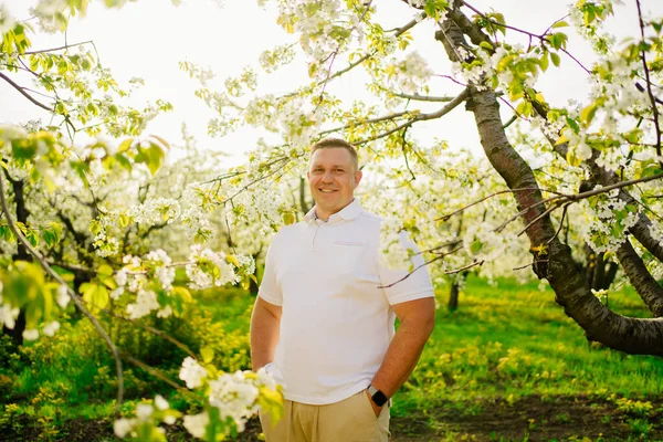 Retrato de un hombre adulto fuerte en un jardín con flores. agricultor empresario. — Foto de Stock