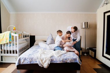 Happy family with a toddler in the bedroom. the first day of the newborn at home clipart