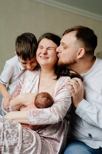 Lycklig familj med småbarn i sovrummet. mamma ammar — Stockfoto