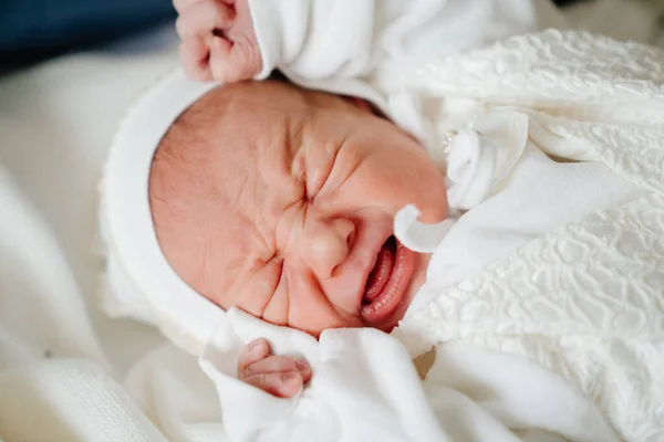 Llorando El bebé recién nacido duerme con ropa blanca. vestimenta para el alta del hospital. — Foto de Stock