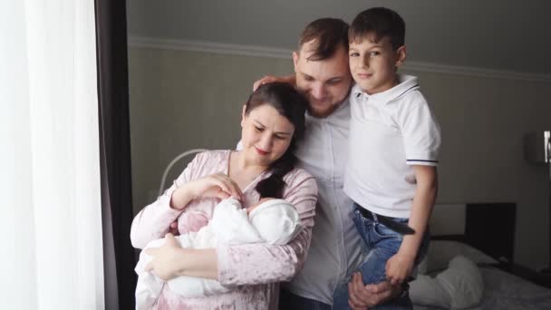 Den första dagen av den nyfödda hemma. Lycklig familj med ett litet barn vid fönstret — Stockvideo