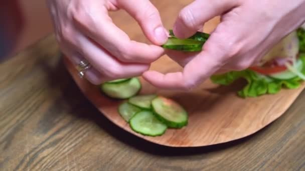 Les mains des femmes étalent le concombre tranché sur une planche à découper en bois à côté de la pita — Video