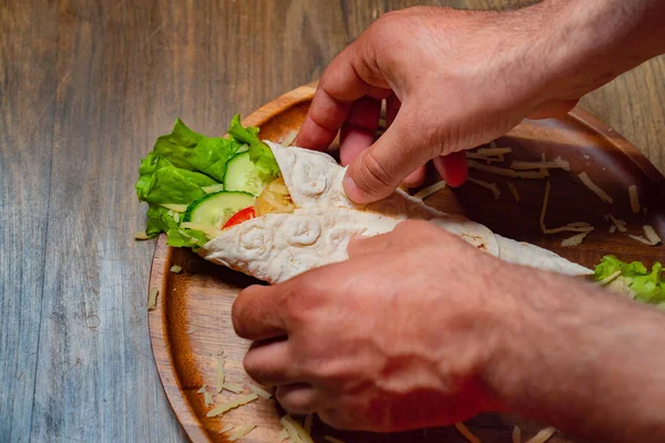 Mãos masculinas desviam pita com legumes e queijo. rolo vegetariano. — Fotografia de Stock