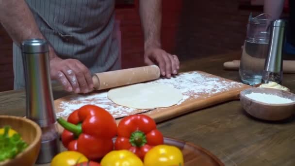 Hombre enrolla la masa en una capa delgada. Cocinar pizza, fideos o pitta en casa — Vídeo de stock
