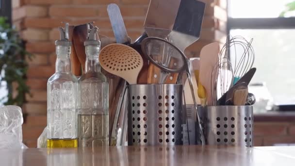 Kitchen table.metal stands with cutlery,glass bottles with olive oil and vinegar — Stock Video