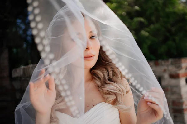 ベールの下に長い波状の髪の幸せな花嫁。結婚式の化粧. — ストック写真