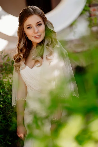 Novia con el pelo ondulado largo en el jardín. Maquillaje de boda. — Foto de Stock