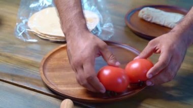 Erkek elleri ahşap bir kesme tahtasına güzel yayılmış domatesler. 