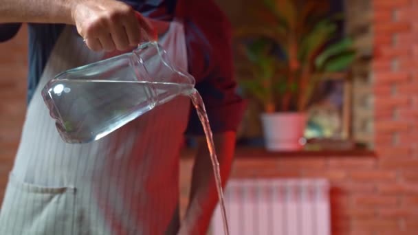 The man pours water from the glass carafe. — Stock Video