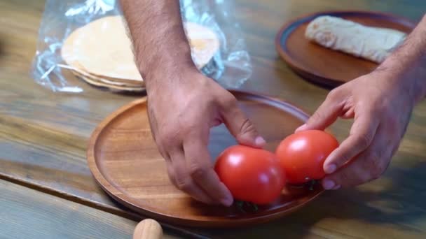 Мужские руки красиво разложили помидоры на деревянной круглой доске. — стоковое видео