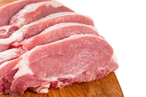 Picado em pedaços de carne de porco crua em uma tábua de corte de madeira em um fundo branco. — Fotografia de Stock