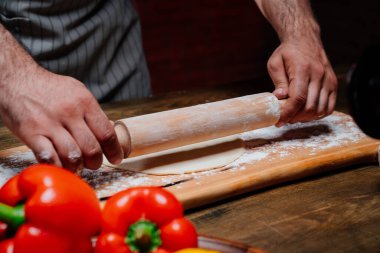 Eller hamuru ince bir tabakaya sarar. Evde pizza, erişte ya da pitta pişiriyorum.