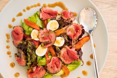 Etli salata, yumurta, sebze ve beyaz tabakta marul.. 