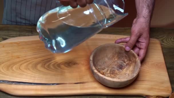 Spruzzi d'acqua. in una boccia di legno versano l'acqua da una caraffa di vetro. — Video Stock