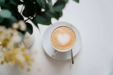 Kalp. Ahşap bir masanın üzerinde kapuçino olan bir fincan. Lezzetli kahve. en üstteki görünüm