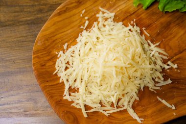 Tahta kesme tahtasında rendelenmiş peynir. Pizza ve makarna malzemeleri.. 