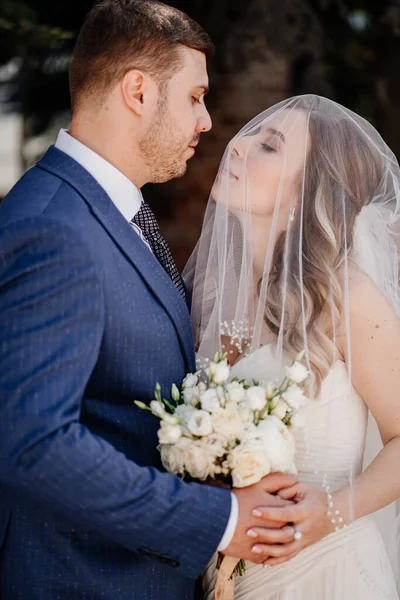 De lieve bruid onder de sluier en bruidegom. mooi en romantisch pasgetrouwden. — Stockfoto