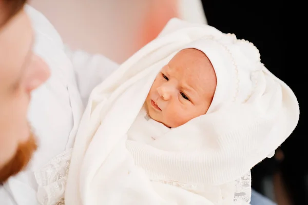 Novorozenec v bílých šatech na rukou rodiče. oděv pro propuštění z nemocnice — Stock fotografie