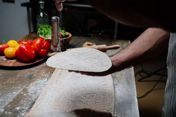 Las manos de los hombres sostienen un pan plano delgado. Cocinar pizza, fideos o pitta en casa —  Fotos de Stock