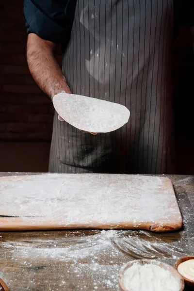 Чоловічі руки тримають тонкий плоский хліб. Готуємо піцу, локшину або піту в домашніх умовах — стокове фото