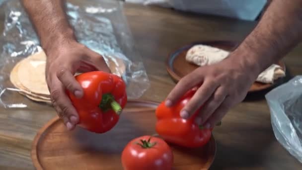 Руки красиво разбрасывают помидоры и сладкий перец на деревянной круглой доске — стоковое видео