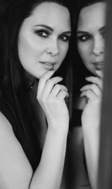 Siyah-beyaz. Aynada siyah saçlı güzel ve seksi bir kadın..