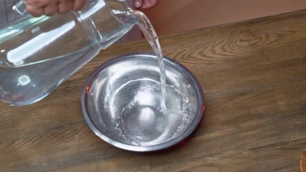 Salpicaduras de agua. en un recipiente de acero inoxidable vierta agua de una jarra de vidrio. — Vídeo de stock