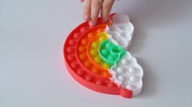 El, gökkuşağı şeklinde çok renkli anti-stres oyuncağıyla oynar.. 