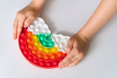 El, gökkuşağı şeklinde çok renkli anti-stres oyuncağıyla oynar.. 
